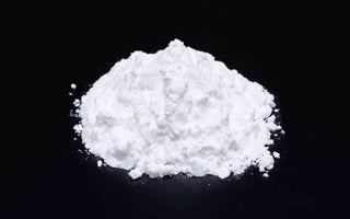 Magnesiumbisglycinat, weißes Pulver auf schwarzer Fläche