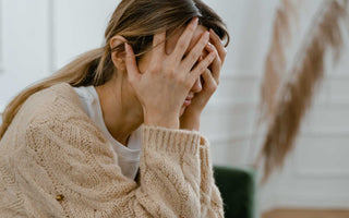 Frau mit Kopf in den Händen (gestresste Haltung)