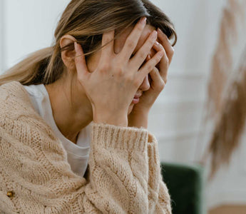 Frau mit Kopf in den Händen (gestresste Haltung)