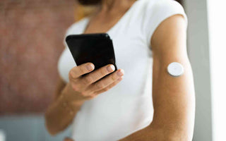 Frau mit Glucosemonitor im Oberarm