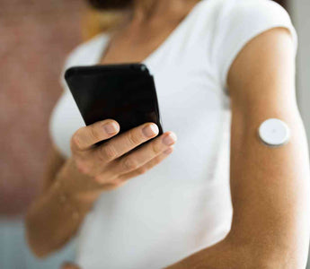 Frau mit Glucosemonitor im Oberarm